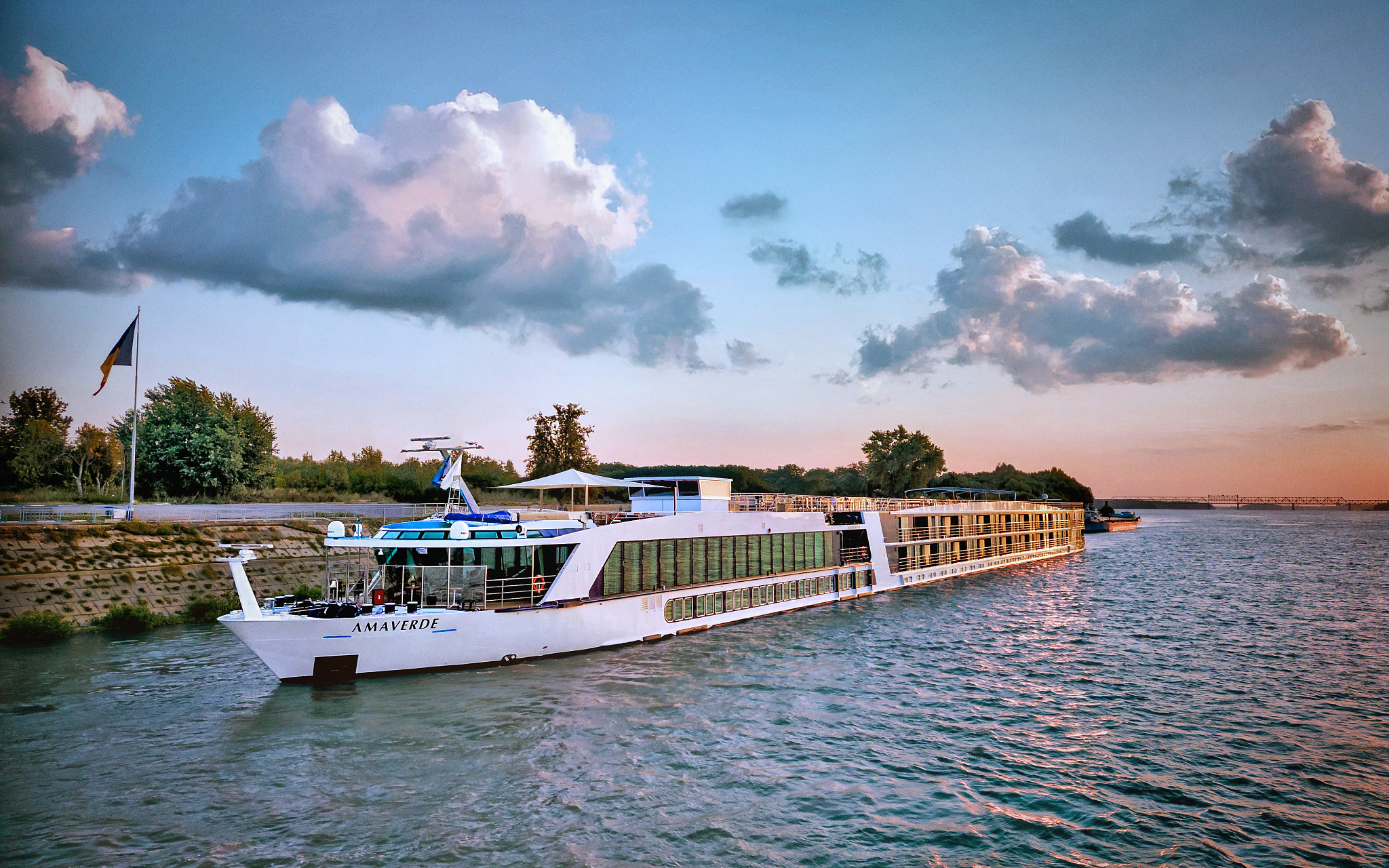 A luxurious river cruise ship named Amaverde docked along a scenic riverbank at golden hour