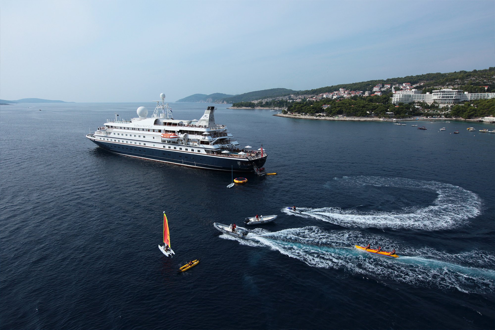 A large expedition cruise ship with distinctive dark hull and white superstructure is anchored