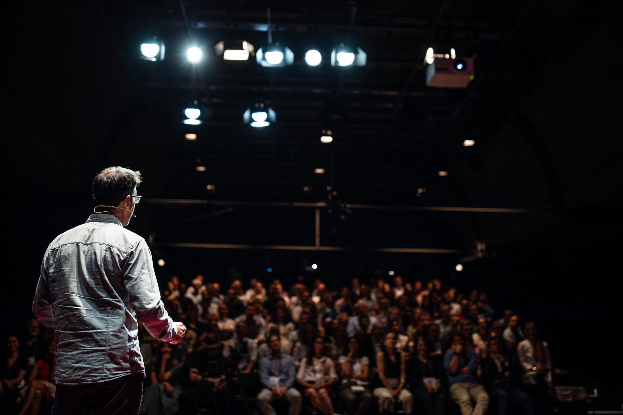 A speaker addressing a large audience in a theater setting, representing corporate events and conferences at sea.