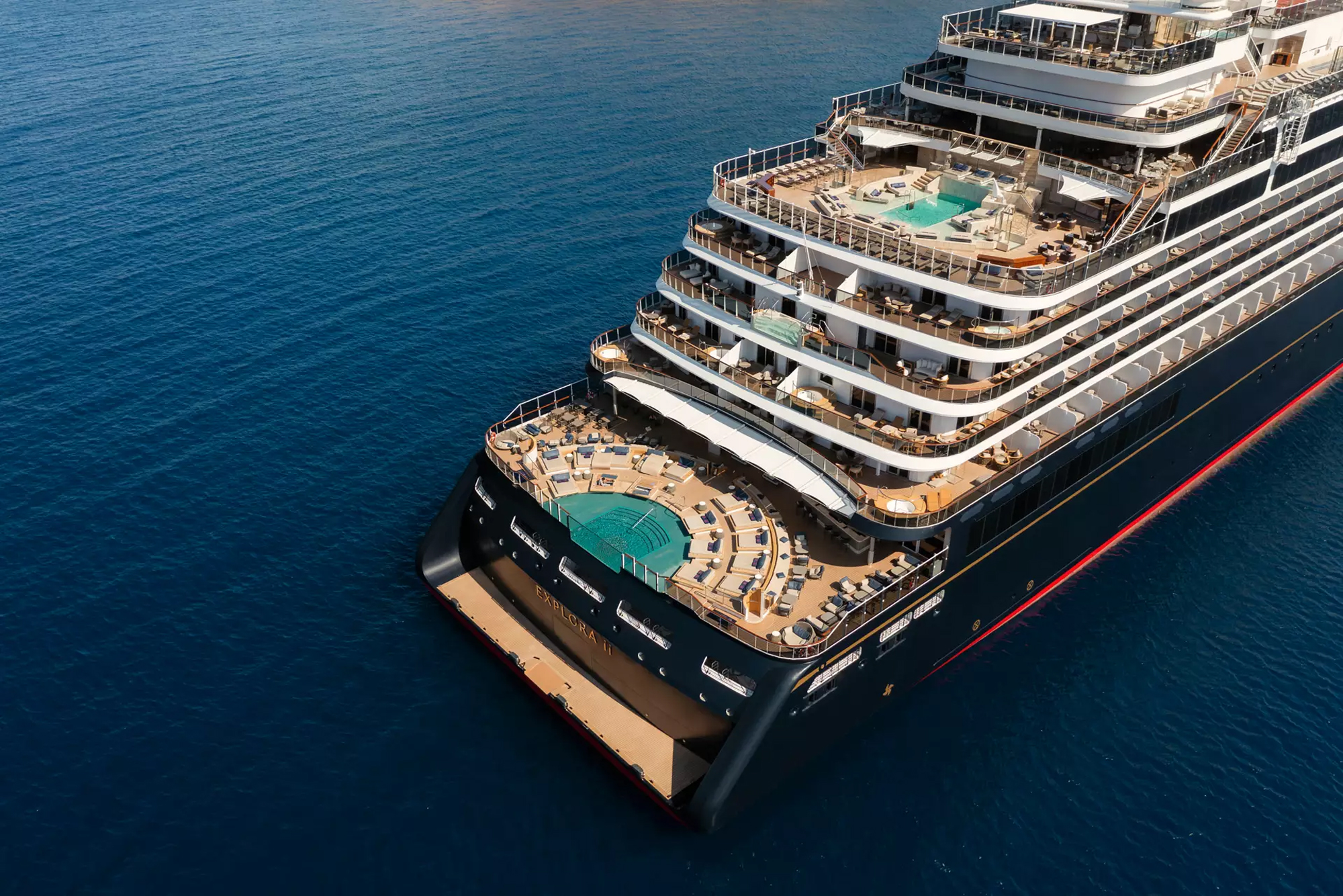 An aerial drone photograph of a luxury cruise ship's pool deck and upper decks. The image shows